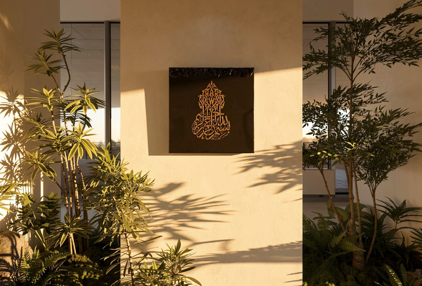 Bismillah by Aiman — gold Islamic calligraphy on a dark resin panel, shown on a warm plaster wall among greenery.