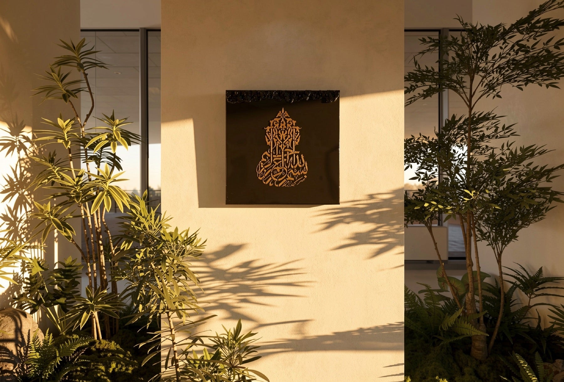 Bismillah by Aiman — gold Islamic calligraphy on a dark resin panel, shown on a warm plaster wall among greenery.